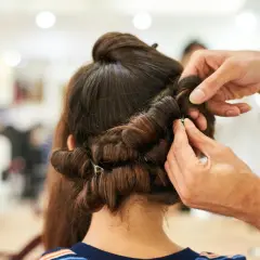 Stylista pokazuje, jak używać wałków do włosów, tworząc loki na ciemnych włosach.