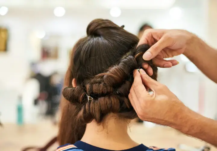 Stylista pokazuje, jak używać wałków do włosów, tworząc loki na ciemnych włosach.