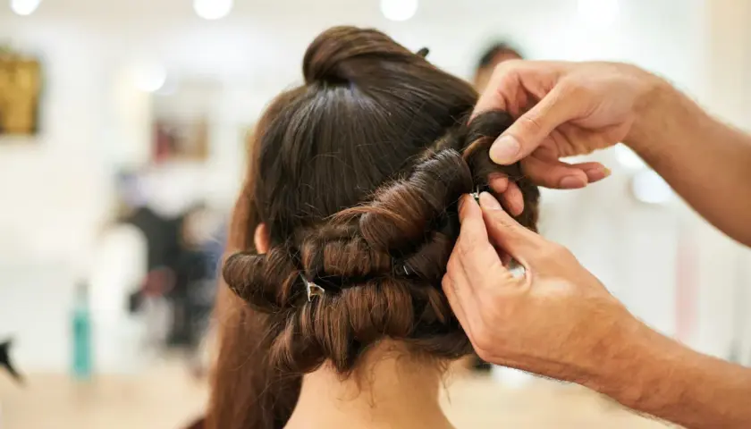 Stylista pokazuje, jak używać wałków do włosów, tworząc loki na ciemnych włosach.