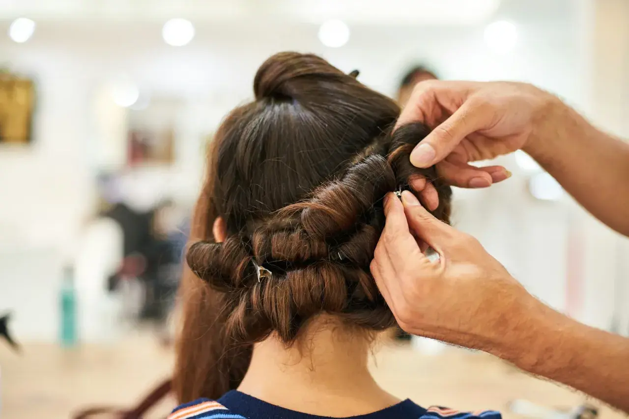 Stylista pokazuje, jak używać wałków do włosów, tworząc loki na ciemnych włosach.